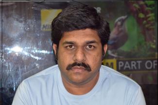 A man with black hair and moustache and white tshirt