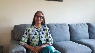 A woman, a cancer survivor of cervical and colorectal cancers sitting on a sofa 