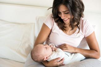 Image of a mother looking down lovingly at a new born baby in her arms 