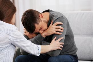 Stock pic of a young woman supporting a young man in distress