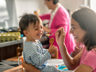 A mother feeding her little child with a spoon 