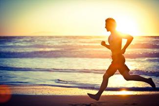 A person running on the beach against the setting sun