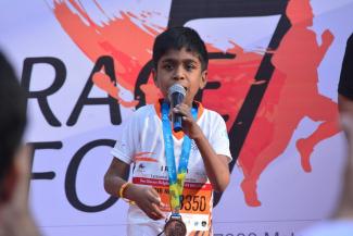 A young boy speaking into a mike in front of a race for rare event