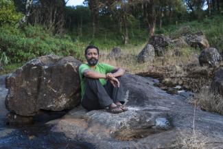 Stage 4 Lung cancer survivor sitting on the rocks in a green t-shirt and jeans 