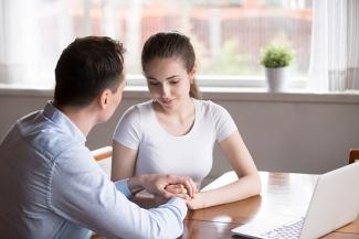 Stock pic of a woman and man holding hands in support