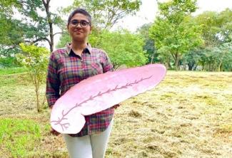 A woman in an open field with a pink board in hand