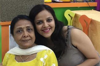 Payal in a brown dress holding her mother in a yellow kurta and white dupatta from behind