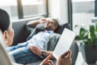 A person lying on a sofa and talking to a counsellor