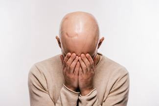 Cancer patient feeling distressed and covering face