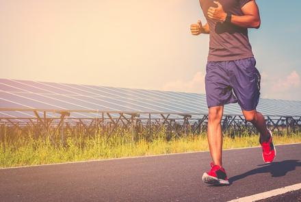 Image: A stock pic of a man running on a road in purple shirts, greyish-purplish t-shirt, red shoes 