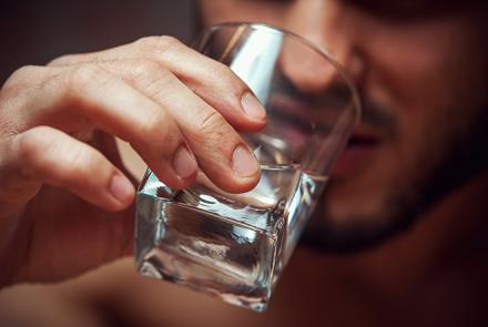 A person drinking alcohol from a glass 