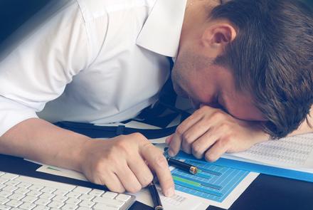 An image of a male person hunched over his work desk