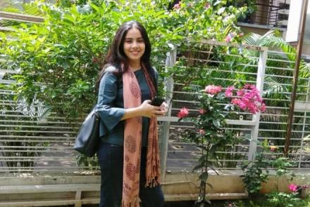 The researcher standing in front of a fence in front of a garden  