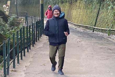 Man stroke survivor jogging wearing a blue jacket and green pants