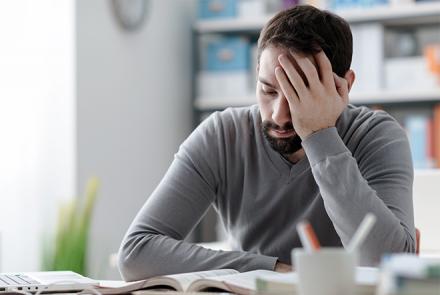 A man in pain and holding his head signifying a migraine flare up