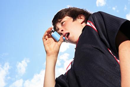 Pic of a young child in a black shirt using an inhaler