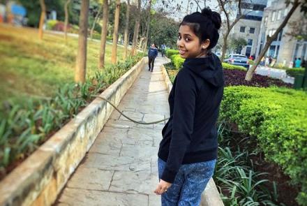 A young woman Shweta Chawre in a black sweater and jeans looking back at the camera as she walks away 