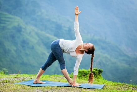 a woman doing trikonasana, triangle pose in an outdoor setting